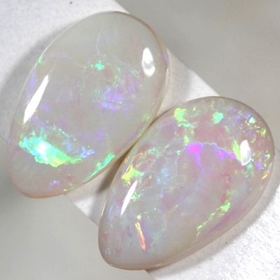 SOLID SEMI BLACK OPALS Matching pair. bright green and orange rolling flashes over a hue of purple